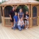 wooden 10 by 14 foot oval gazebo with happy family standing in front