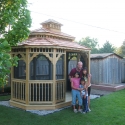 8 by 14 foot wooden oval gazebo with happy family standing in the front